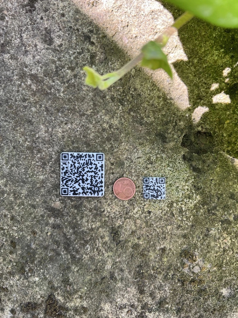 Tiny printed QR code next to a larger QR code and a one-cent coin